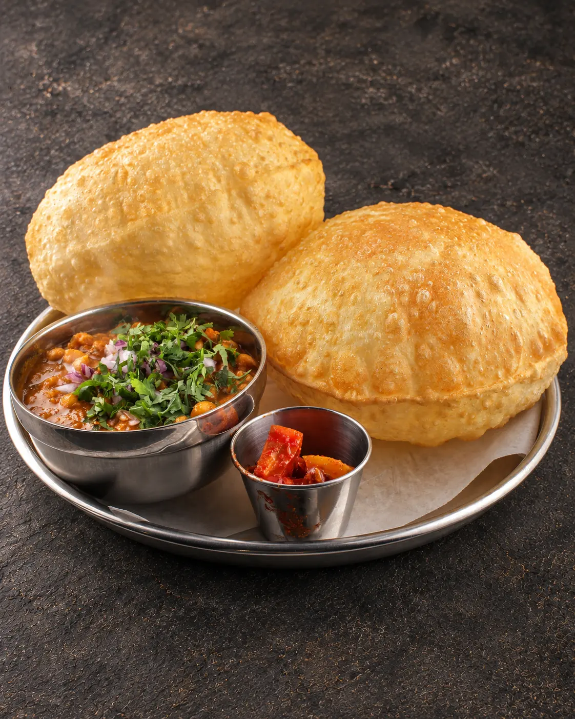 Chhole Batura: puffed fried bread with a bowl of spiced chickpea gravy and lemon pickle