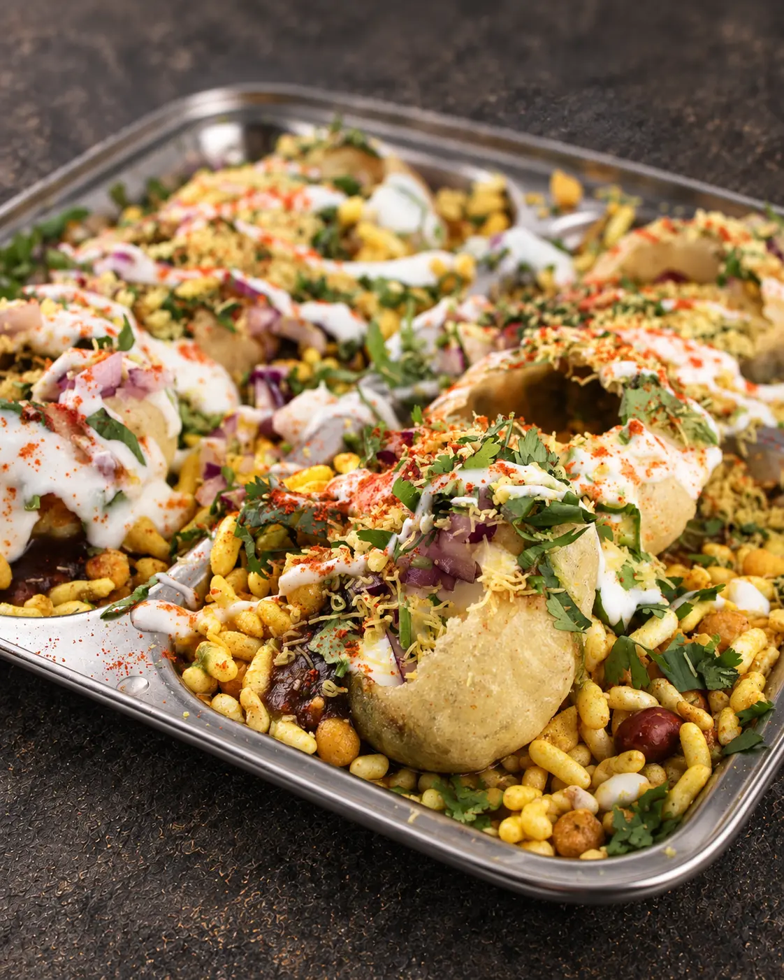 Dahi Puri: crisp semolina shells filled with potato and chickpeas, topped with yogurt and sev