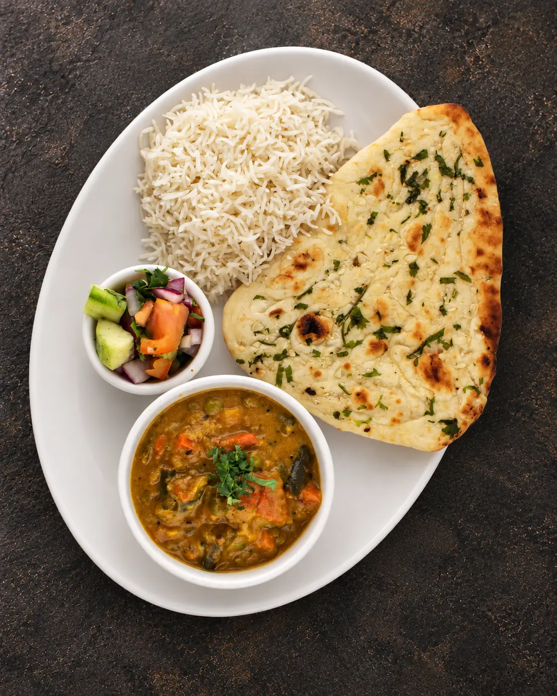 Vegetable Korma in a creamy gravy served with garlic naan, basmati rice and salad